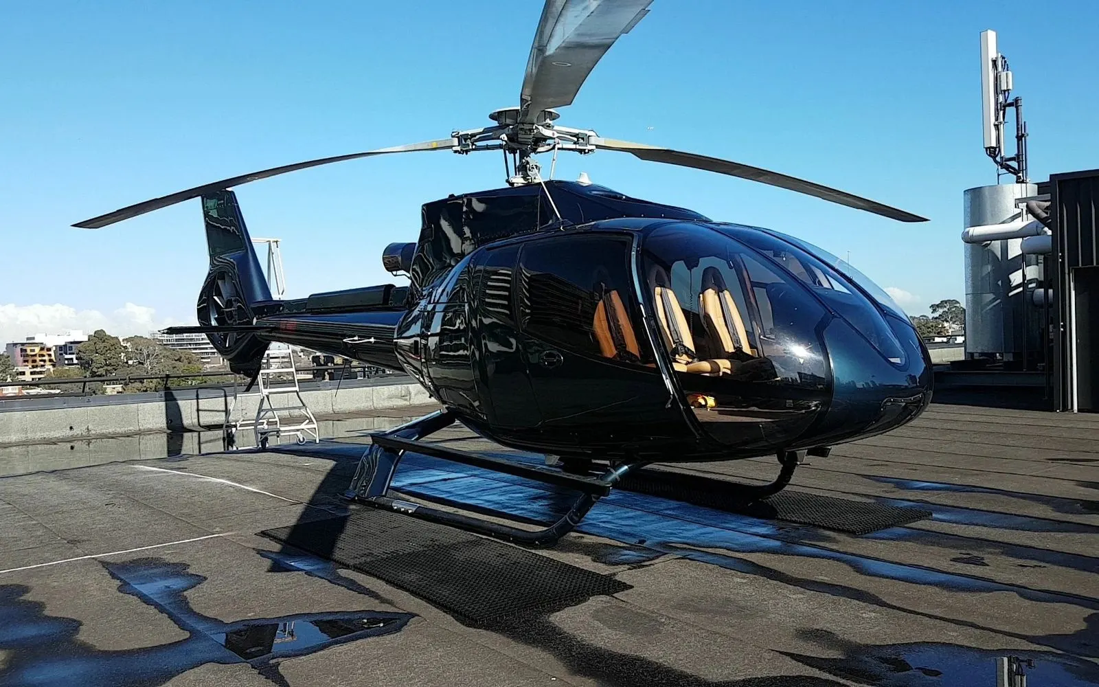 Gloss black helicopter on a rooftop helipad with a mirror finish