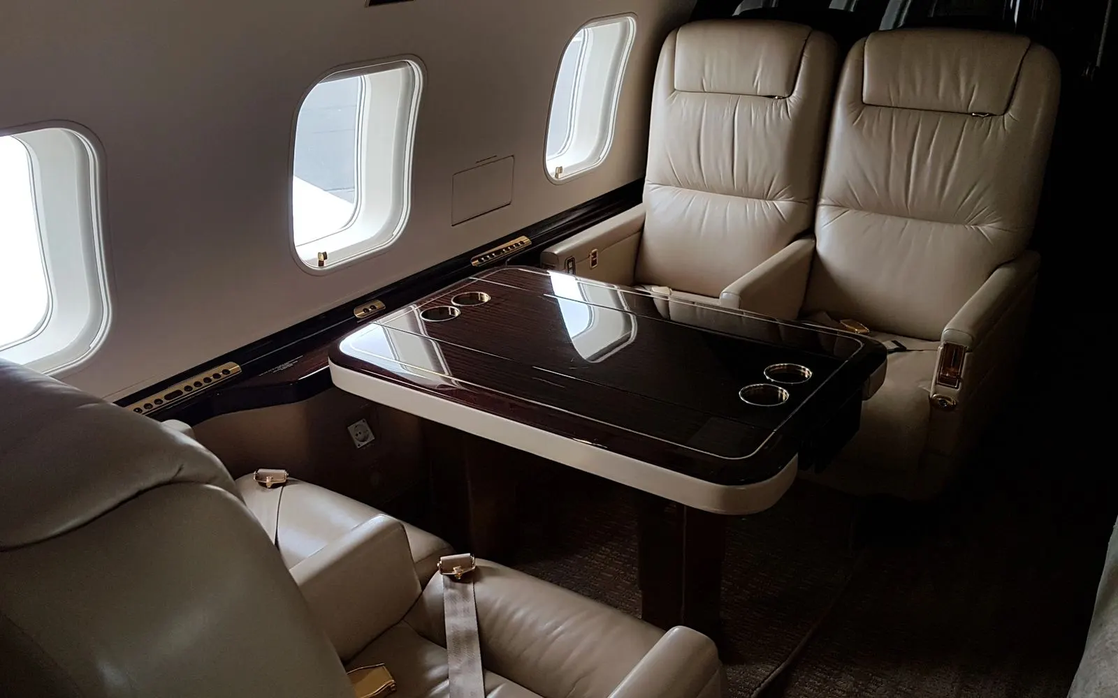 Business jet conference grouping with tan leather seats and polished table