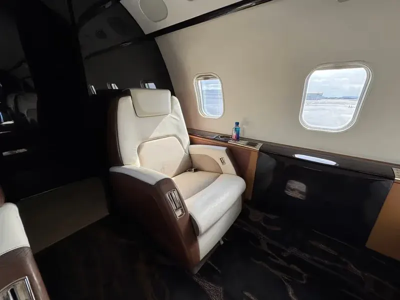 Business jet executive seat beside a stone side table and cabin window